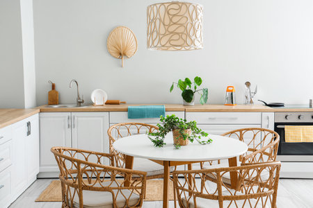 Interior of light kitchen with white counters, electric oven and dining tableの写真素材