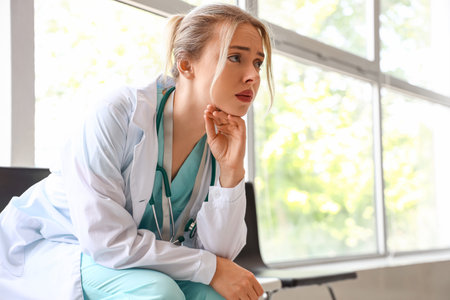 Sad female doctor sitting in clinicの写真素材