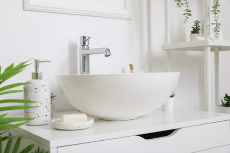 Sink bowl and bath accessories on chest of drawers in bathroomの写真素材