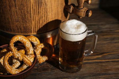 Mug of cold beer, barrel and pretzels on wooden background.の写真素材
