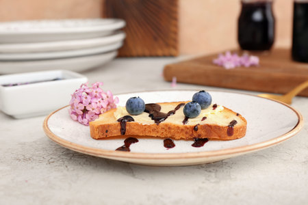 Plate with sweet blueberry jam toast and flowers on table