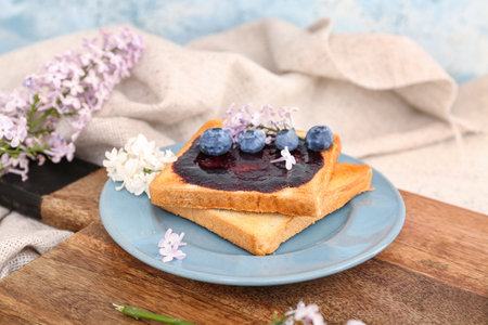 Plate with sweet blueberry jam toasts and lilac flowers on white table, closeupの写真素材