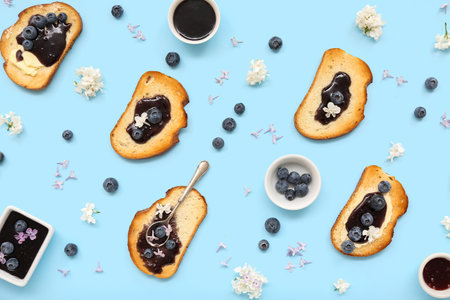 Composition with delicious jam toasts, blueberries and flowers on blue backgroundの写真素材