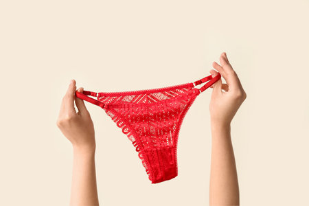 Female hands with stylish red panties on light background, closeupの写真素材