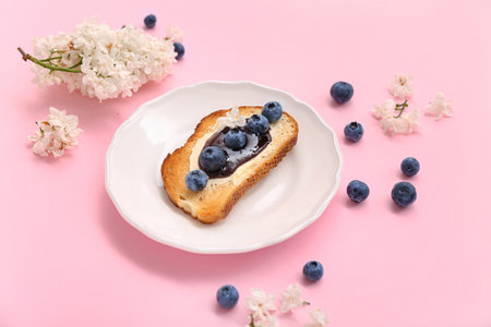 Plate with delicious jam toast, blueberries and flowers on pink backgroundの写真素材