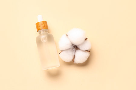Bottle of essential oil and cotton flower on color backgroundの写真素材