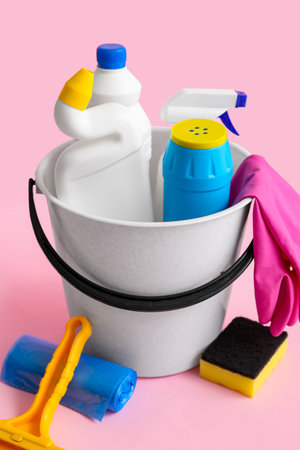 Bucket with different cleaning supplies on pink backgroundの写真素材