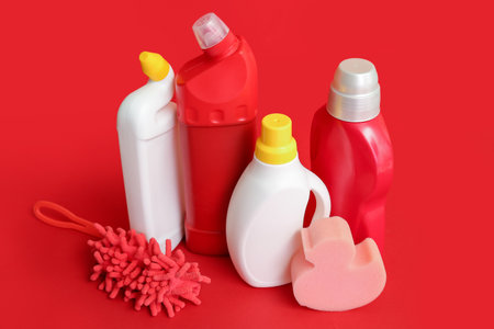 Different cleaning supplies on red backgroundの写真素材