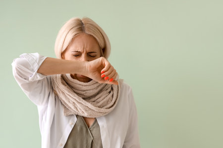 Ill mature woman with runny nose on green backgroundの写真素材