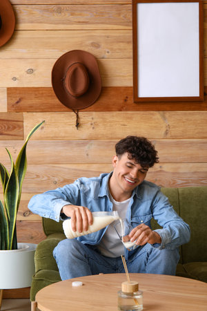 Young man pouring milk into glass at homeの写真素材