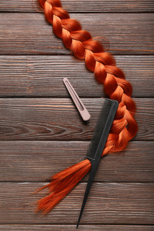 Braided ginger hair, comb and clip on wooden backgroundの写真素材