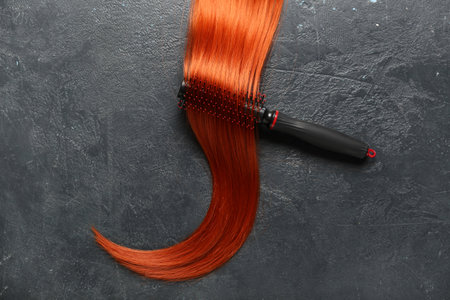 Ginger hair strand and brush on dark background, closeupの写真素材