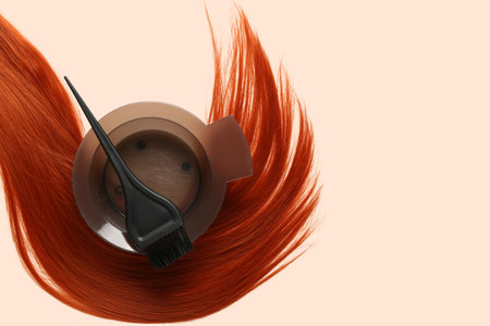 Ginger hair strand, bowl for hair dye and brush on color background, closeupの写真素材