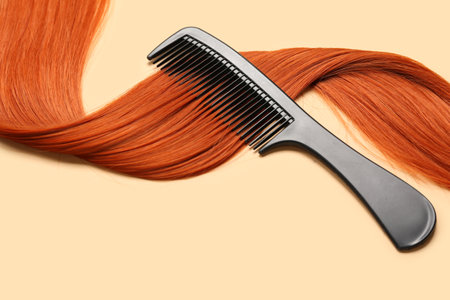 Ginger hair strand with comb on color background, closeupの写真素材