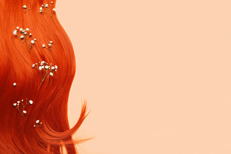 Ginger hair strand with beautiful gypsophila flowers on color backgroundの写真素材