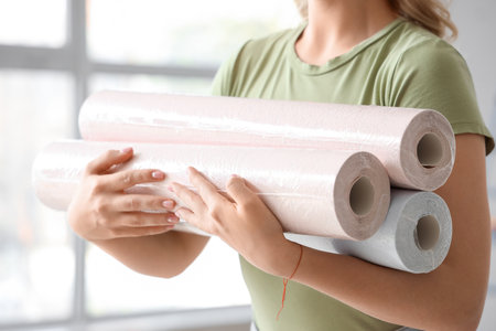 Young woman with wallpaper rolls at home, closeupの写真素材