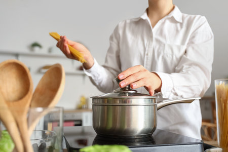 Young woman boiling spaghetti in kitchen, closeupの写真素材
