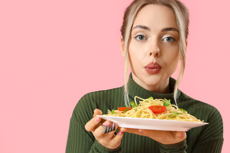Young woman with tasty pasta on pink background, closeupの写真素材