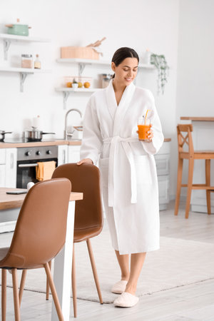 Young woman with glass of vegetable juice in the kitchenの写真素材