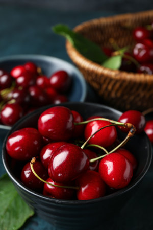 Bowls with sweet cherries on blue background, closeupの写真素材