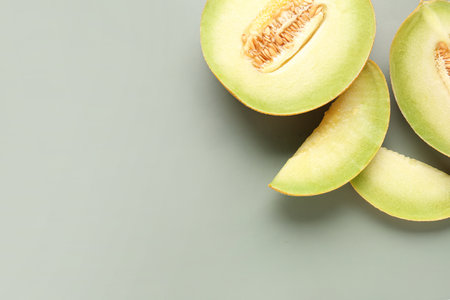 Half of sweet melon with pieces on gray backgroundの写真素材