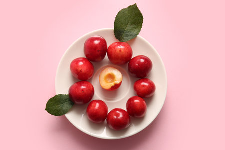Plate with sweet cherry and leaves on pink backgroundの写真素材