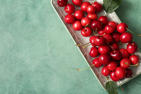 Plate with sweet cherry on green backgroundの写真素材