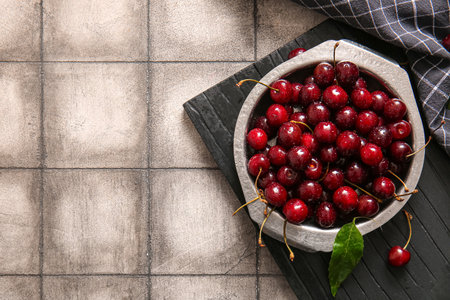Board with metal plate of sweet cherries on gray tile backgroundの写真素材