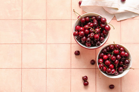 Bowls with sweet cherry on pink tile tableの写真素材