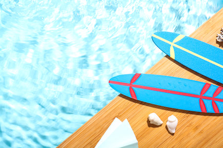 Composition with mini surfboards, umbrella and seashells on edge of swimming poolの写真素材