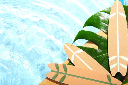 Composition with mini surfboards and palm leaf on edge of swimming pool