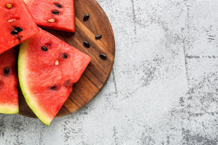 Board with pieces of fresh watermelon and seeds on gray backgroundの写真素材