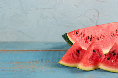 Pieces of fresh watermelon on blue wooden tableの写真素材