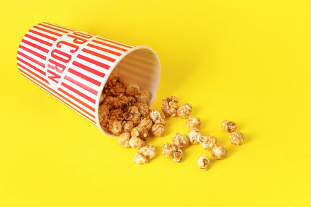 Bucket with tasty popcorn on yellow backgroundの写真素材