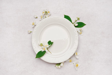 Composition with plate and beautiful jasmine flowers on light background