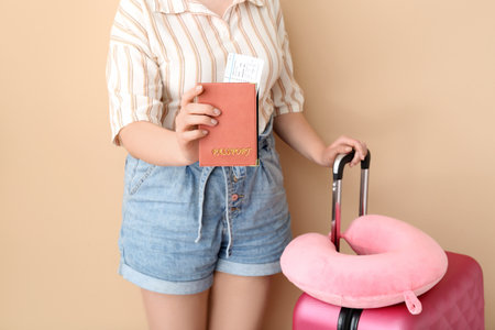 Young woman with passport, ticket, suitcase and travel pillow on orange background. travel conceptの写真素材