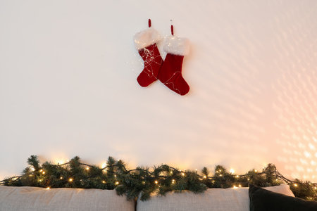 Christmas socks with glowing lights on light wall in living roomの写真素材
