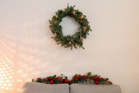 Glowing Christmas wreath on light wall in living roomの写真素材