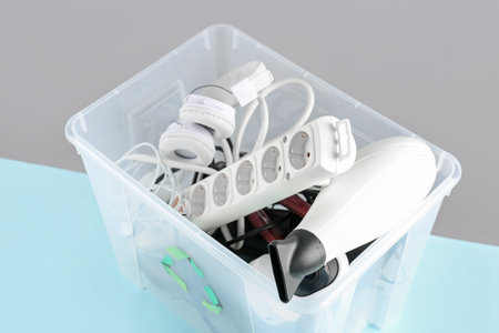 Recycle bin with different household appliances on color background