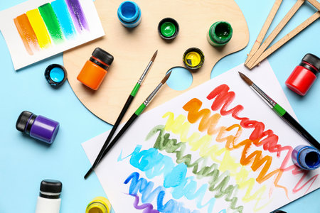 Composition with different paints, brushes and rainbow color palette on blue backgroundの写真素材