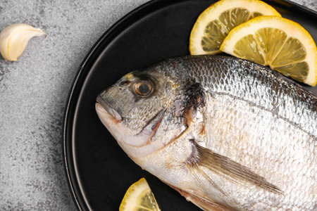 Tray of raw dorado fish with lemon on light backgroundの写真素材
