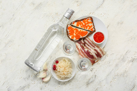 Shots and bottle of cold vodka and snacks on light backgroundの写真素材