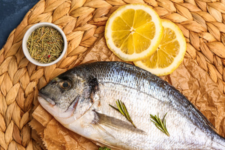 Raw dorado fish with lemon and herbs on tableの写真素材