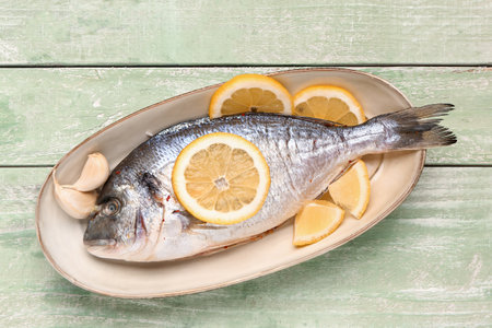 Plate of raw dorado fish with lemon on green wooden backgroundの写真素材