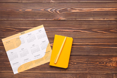 Calendar, notebook and pen on wooden background