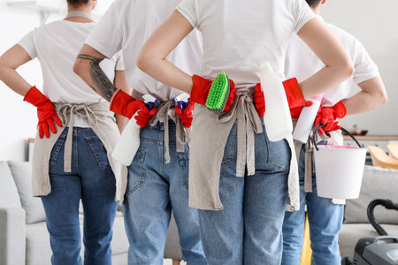 Young janitors with cleaning supplies in kitchen, back viewの写真素材