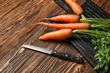 Board of fresh carrots with leaves on wooden backgroundの写真素材