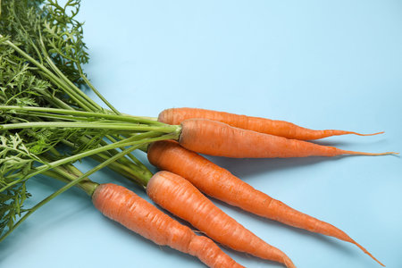 fresh carrots with leaves on blue background