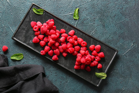 Tray with fresh raspberries on dark table