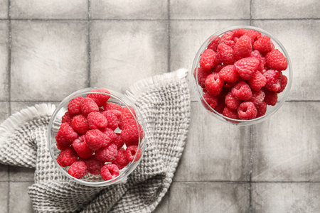 Glasses with fresh raspberries on gray tile tableの写真素材